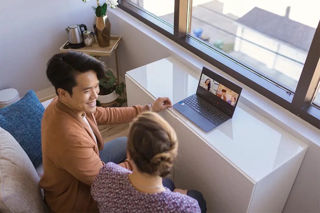 A man and a woman smile as they look at each other during an online couples therapy session.